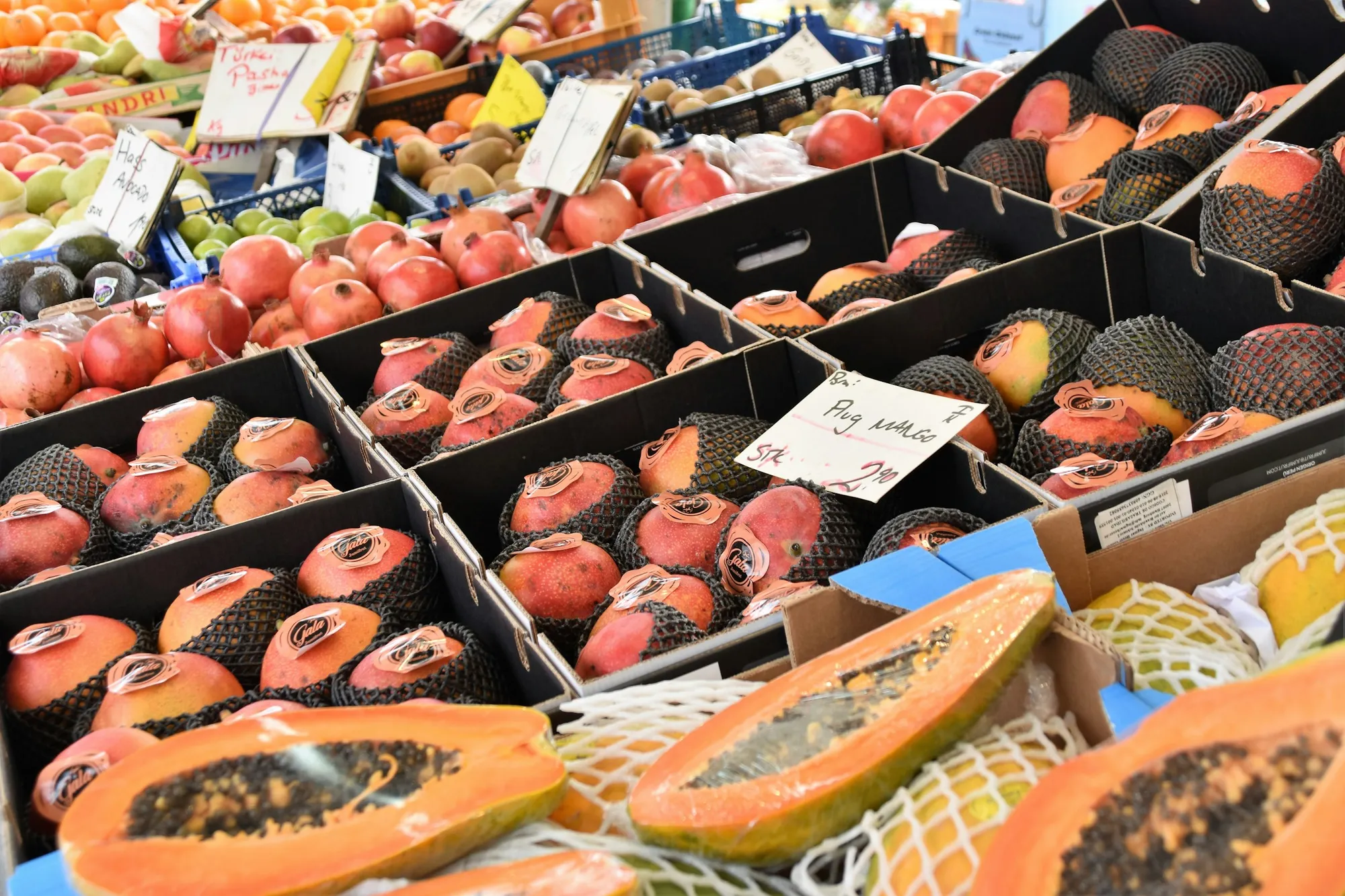 Halved papayas and ripe mangoes packed in open produce boxes at a market